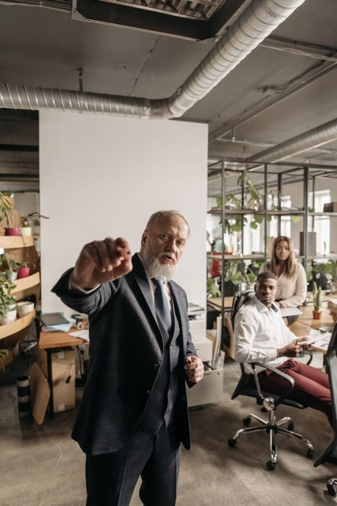 An executive in a suit leads a meeting with colleagues in a modern office space.