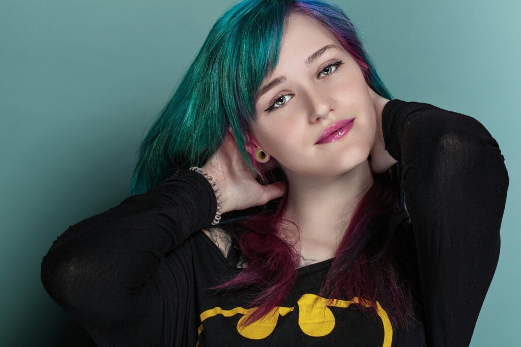 Stylish portrait of a woman with colorful hair and vibrant makeup in a studio setting.