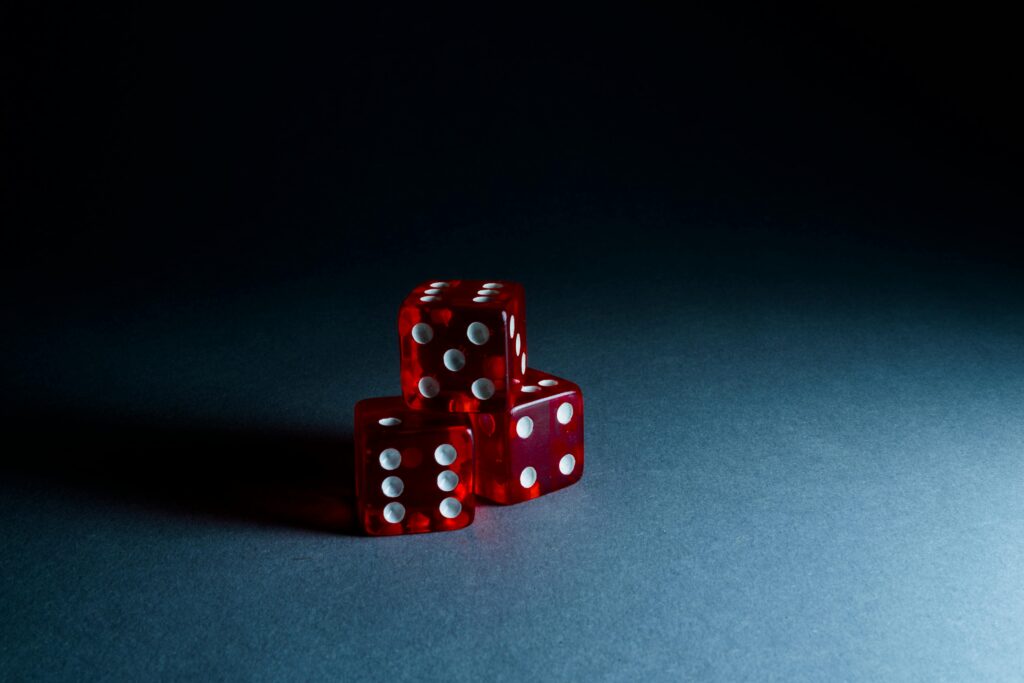 Three red transparent dice stacked on a dark surface, highlighting their reflective surfaces and dots.