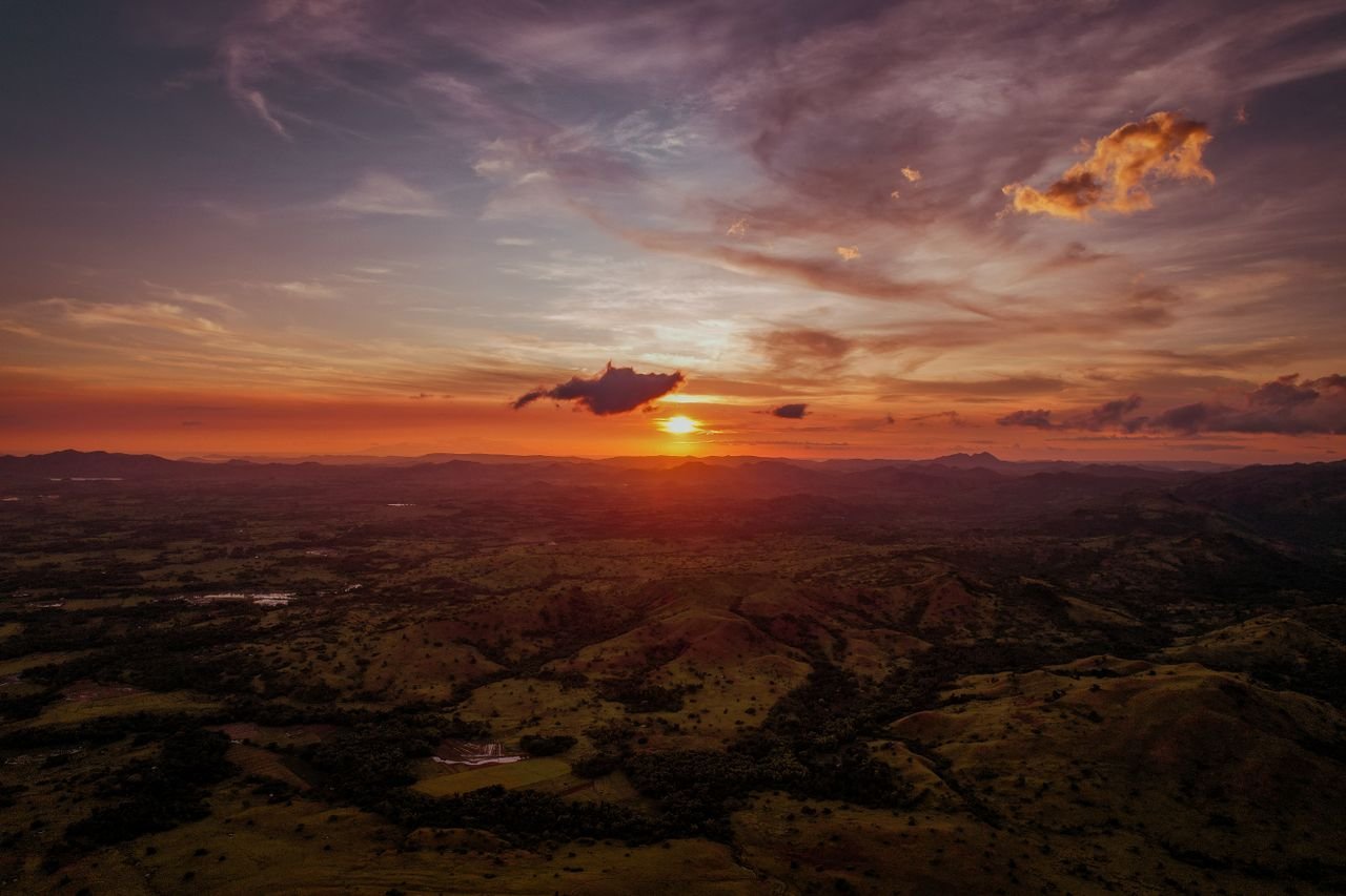 A breathtaking aerial view of a vibrant sunset over the rolling hills of Milagros, Bicol, Philippines.